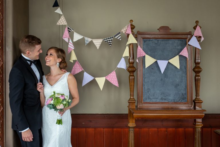 hääpari katsoo toisiaan silmiin rakastavasti taustallaan hääkoristeita